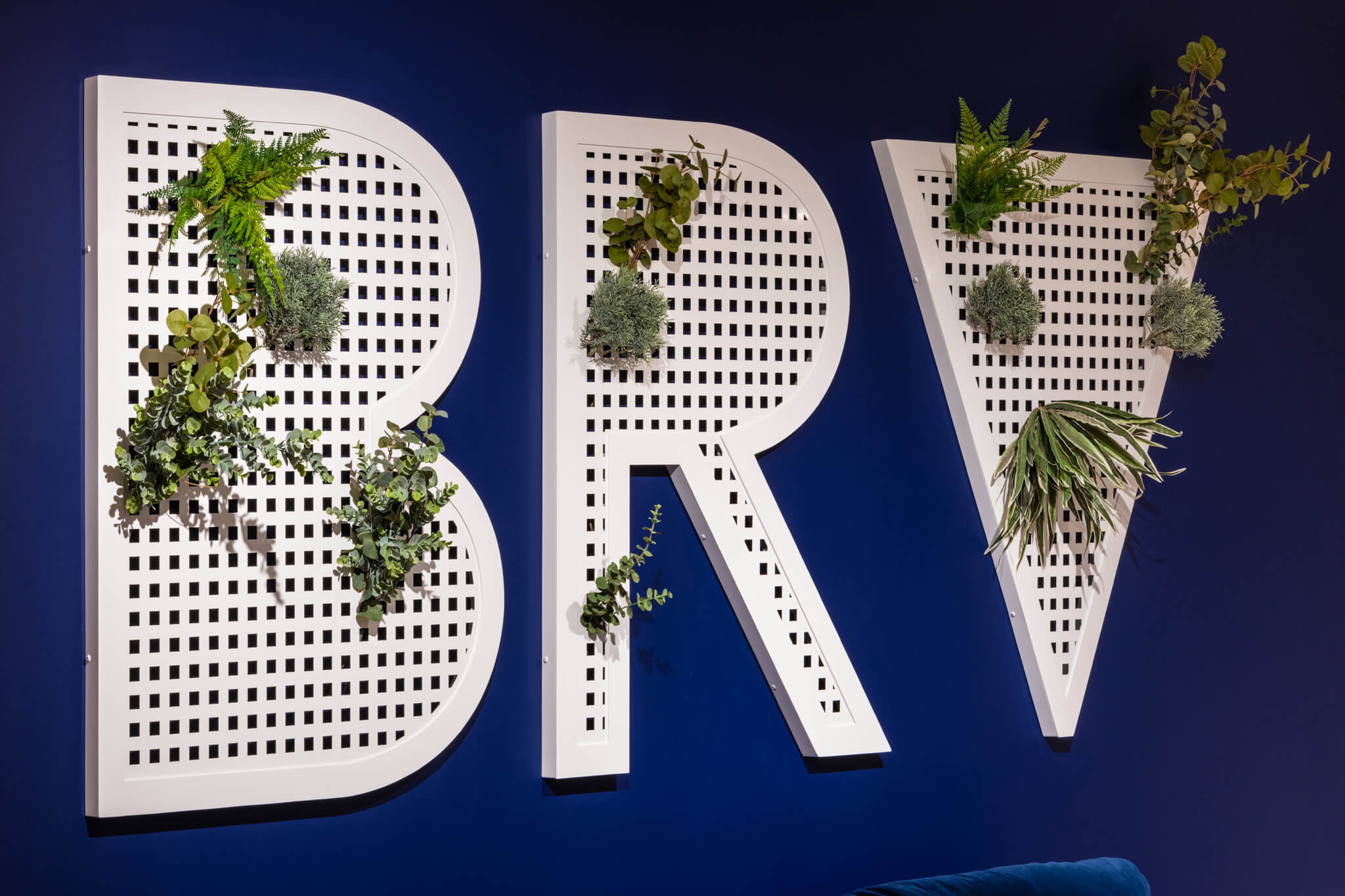 a white sign with plants coming off of it on a blue wall that reads B R V