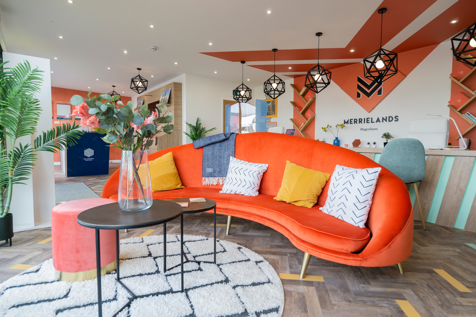 orange curved sofa with a coffee table in front of it holding a vase of flowers