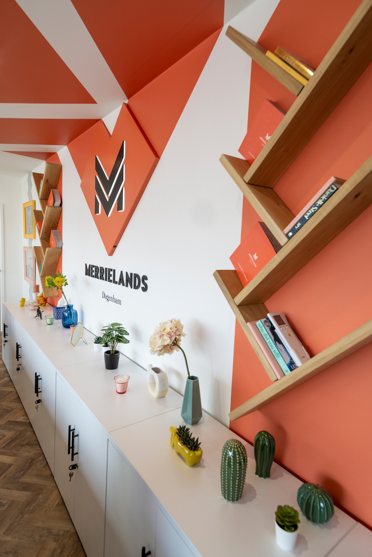 Merrielands logo on a wall with wooden shelves either side of it
