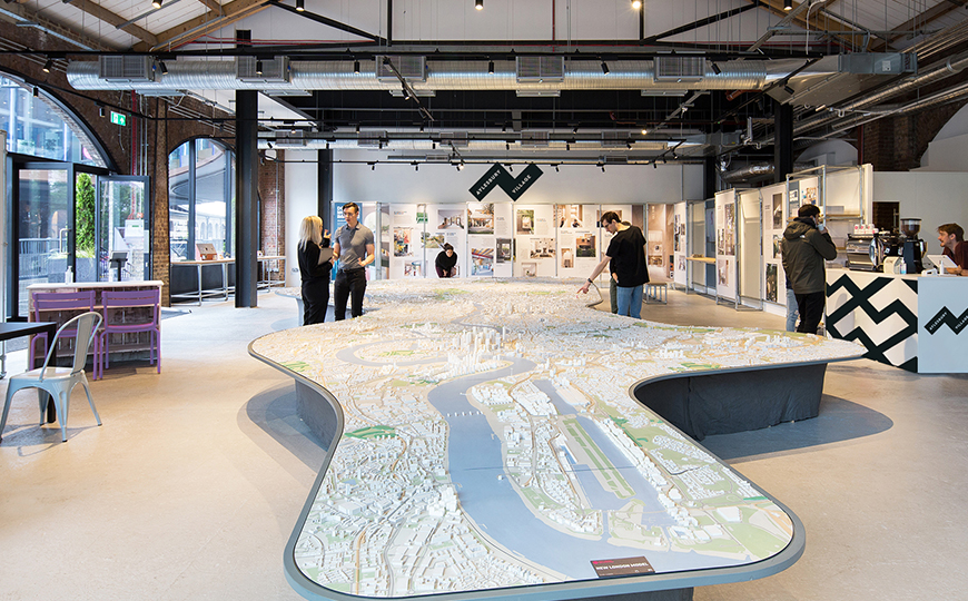 A marketing suite with people looking at a large 3D model of The River Thames and the structures that run along it