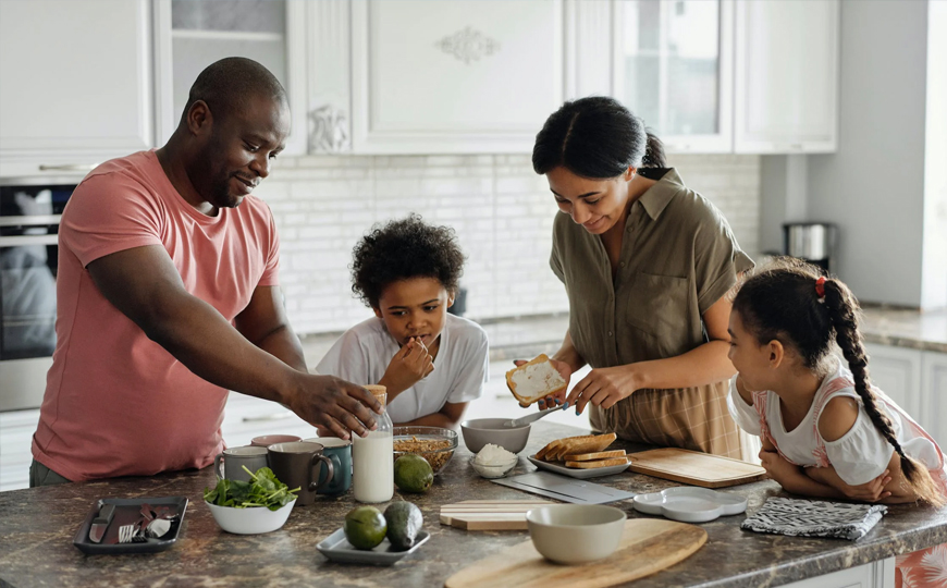 Family of four with young children making food on their kitchen counter