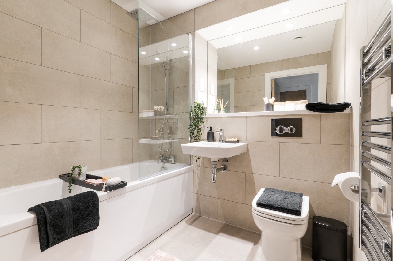 modern bathroom with tiled walls and a large mirror opposite the sink
