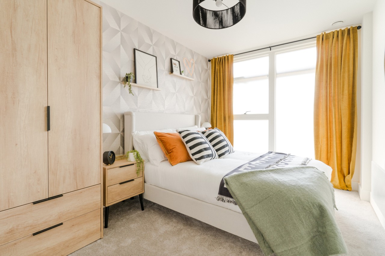 cosy bedroom with a double bed, orange curtains and pillows
