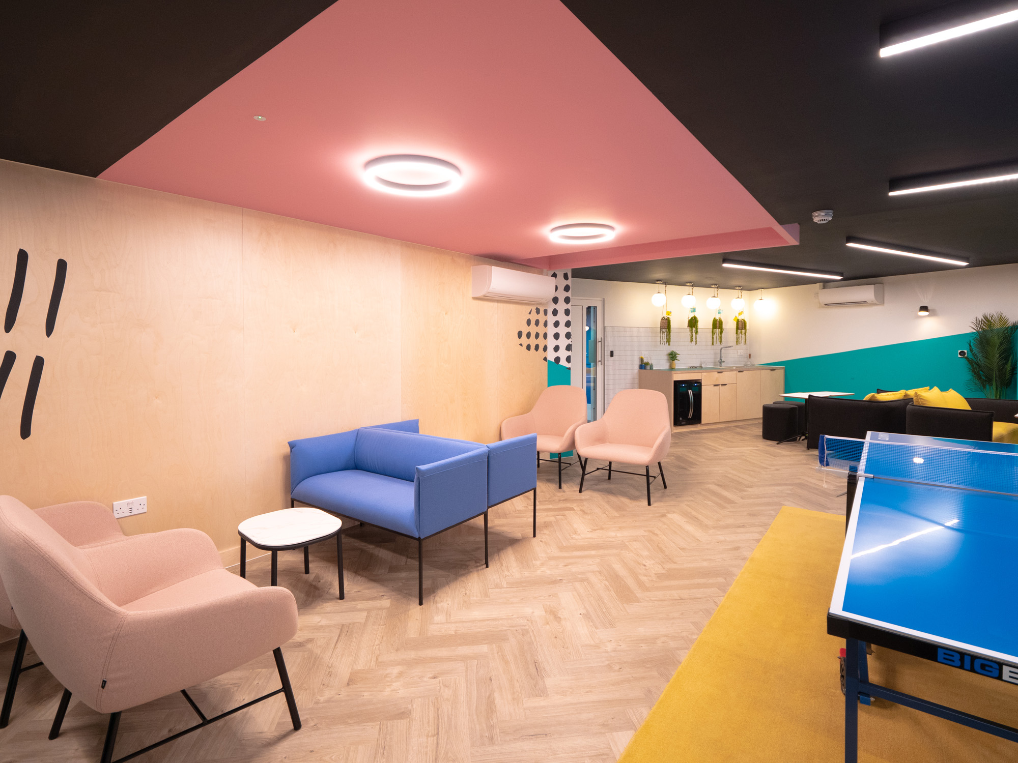 Brightly coloured communal area with a ping pong table and lots of seats