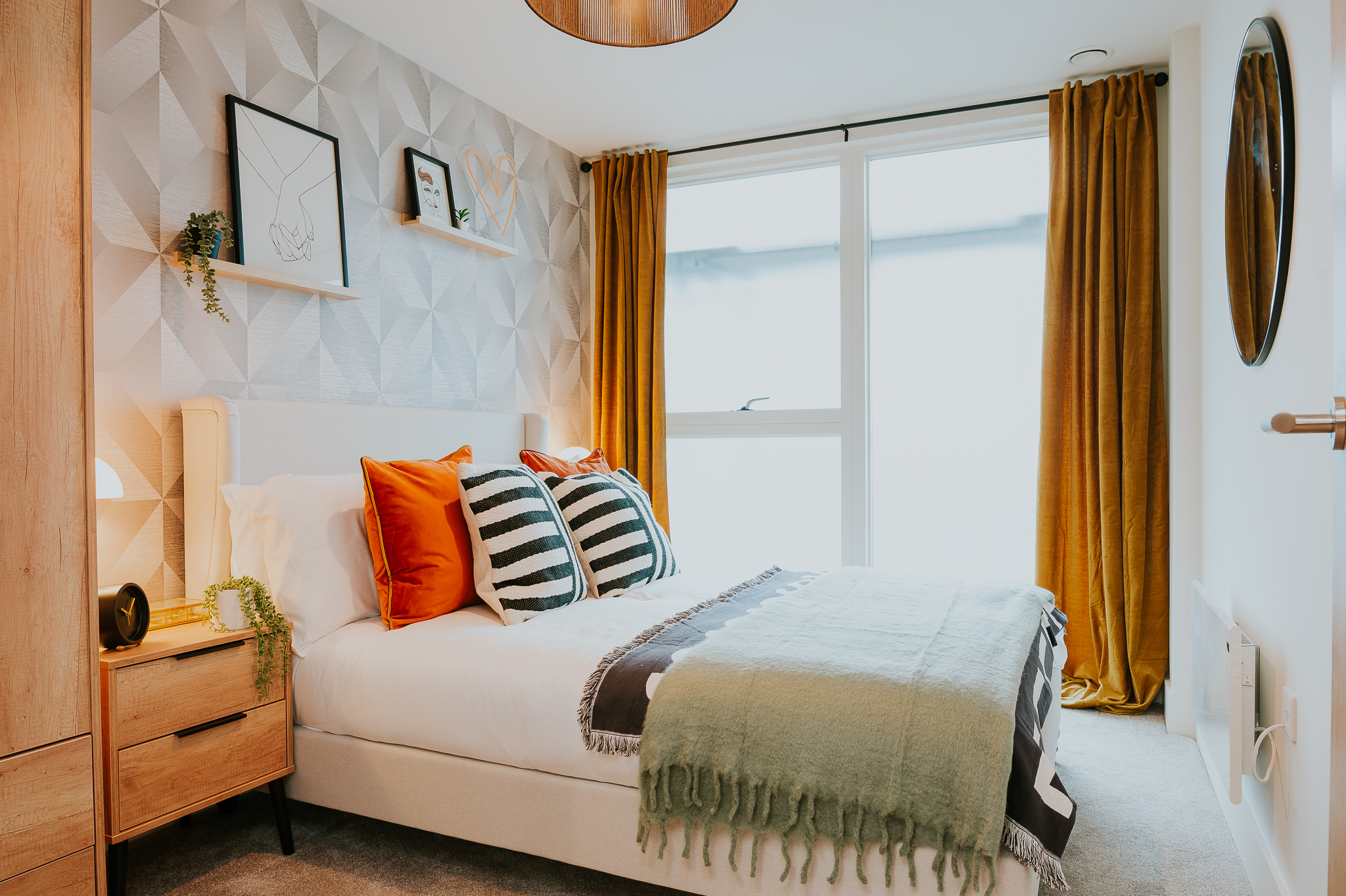 cosy bedroom with a double bed, orange curtains and pillows