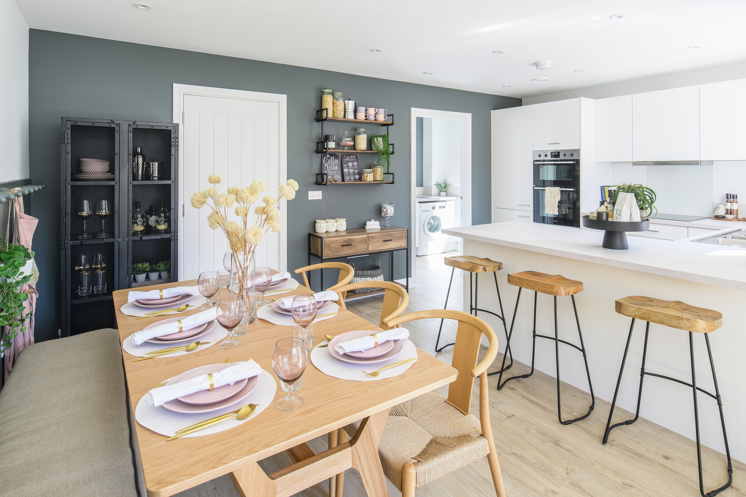A kitchen dining area that uses white cabinets and lots of wooden furniture such as the dinner table