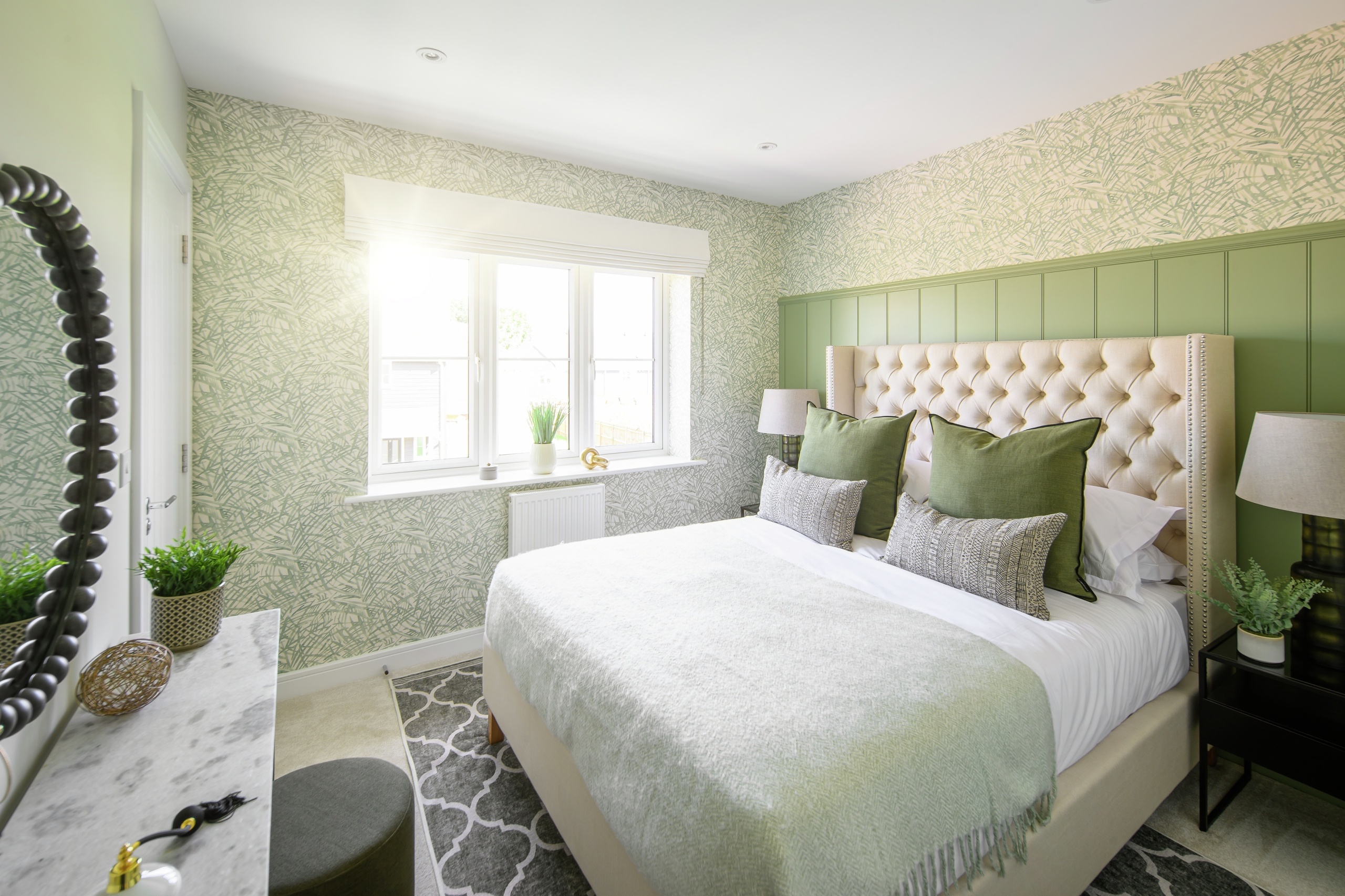 A white and green bedroom with a large double bed in the centre